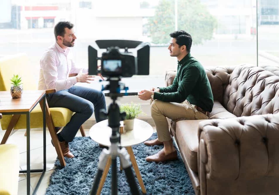 journalist interviewing businessman while recording in video camera at office