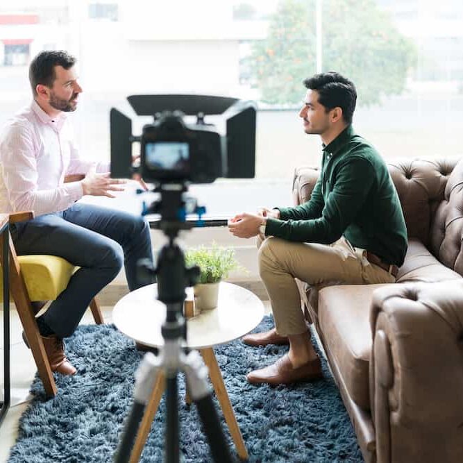 journalist interviewing businessman while recording in video camera at office